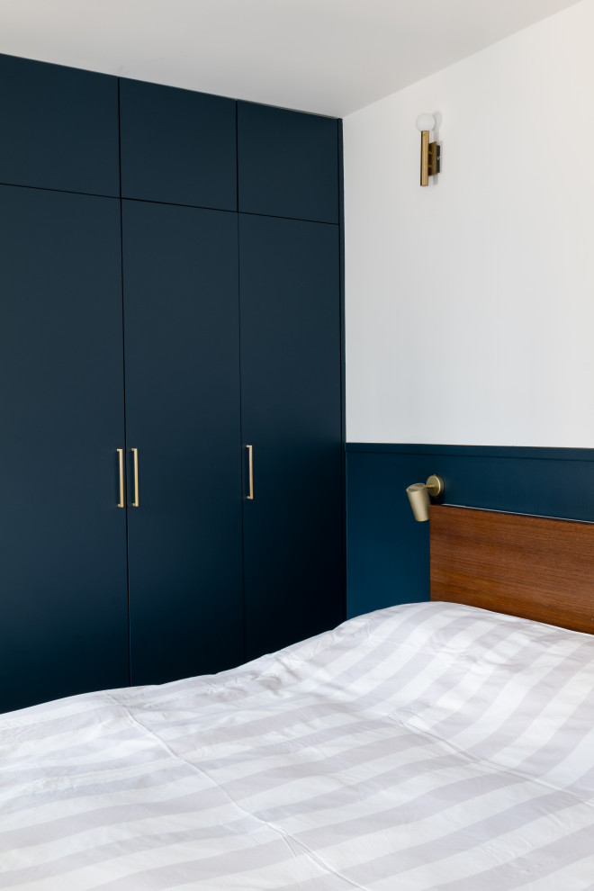 Aménagement d'une petite chambre parentale moderne avec un mur bleu et dressing.