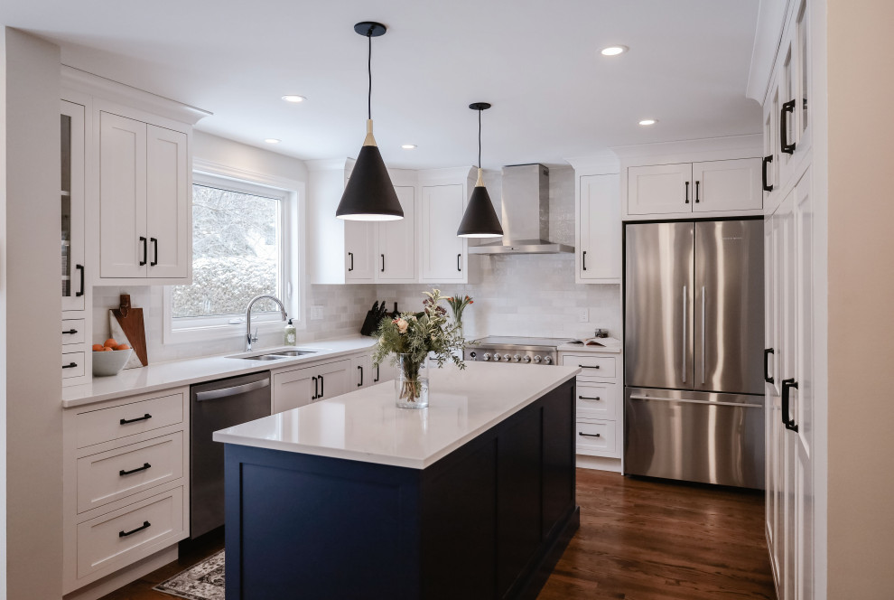 Inspiration for a small transitional u-shaped medium tone wood floor and brown floor eat-in kitchen remodel in Ottawa with an undermount sink, shaker cabinets, white cabinets, quartz countertops, white backsplash, subway tile backsplash, stainless steel appliances, an island and white countertops