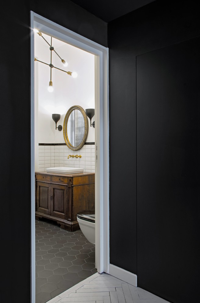 Design ideas for a mid-sized contemporary powder room in Other with distressed cabinets, a two-piece toilet, porcelain tile, porcelain floors, a drop-in sink, wood benchtops, black tile and white tile.