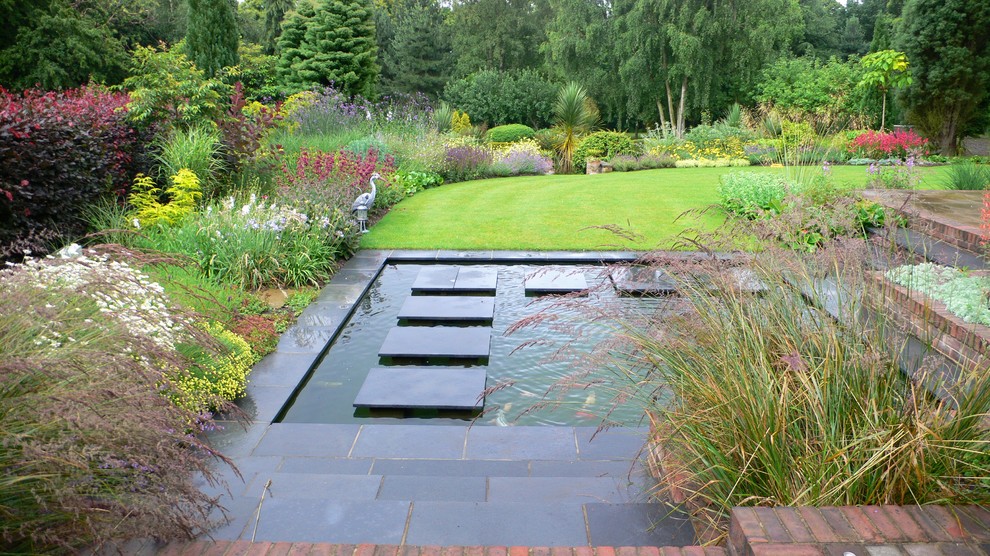 Design ideas for a large asian backyard formal garden for summer in Essex with a water feature and brick pavers.