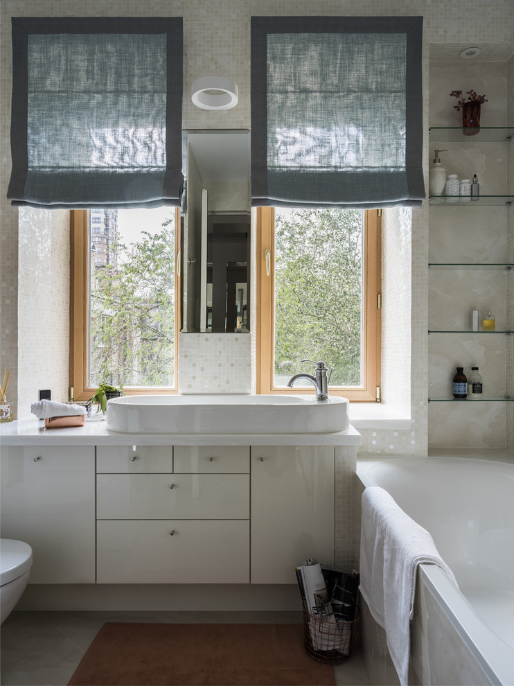 This is an example of a small contemporary bathroom in Moscow with flat-panel cabinets, white cabinets, white tile, beige tile, a vessel sink, white benchtops, a drop-in tub and beige walls.