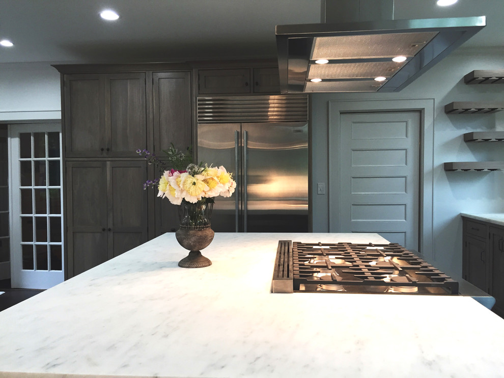 Transitional ceramic tile and black floor kitchen photo with an undermount sink, shaker cabinets, medium tone wood cabinets, marble countertops, white backsplash, ceramic backsplash, stainless steel appliances and an island