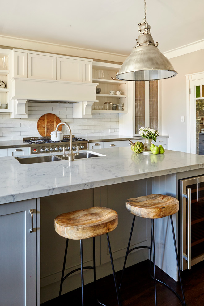 Large traditional l-shaped eat-in kitchen in Sydney with a double-bowl sink, shaker cabinets, white cabinets, quartz benchtops, white splashback, ceramic splashback, stainless steel appliances, medium hardwood floors and with island.