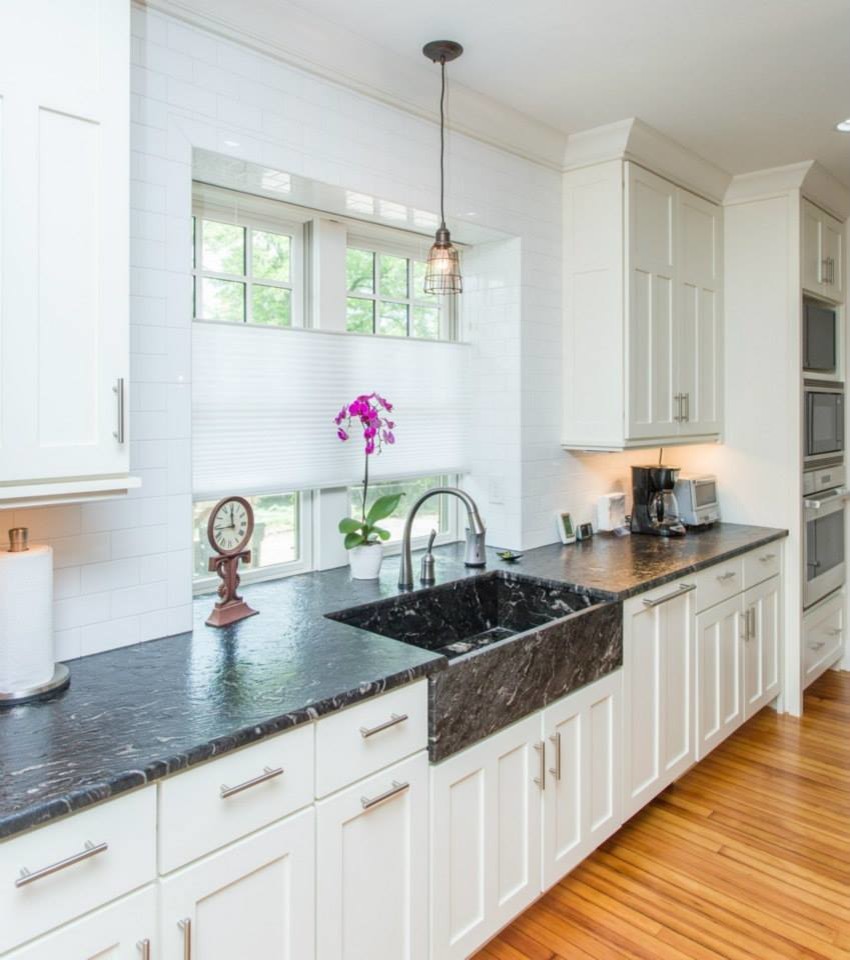 Mid-sized transitional light wood floor kitchen photo with a farmhouse sink, shaker cabinets, white cabinets, granite countertops, white backsplash, ceramic backsplash and stainless steel appliances