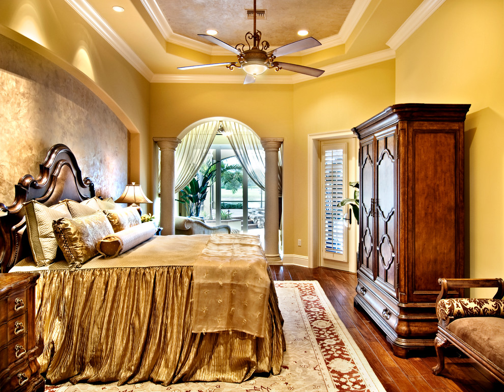 Inspiration for a large mediterranean master bedroom in Miami with yellow walls, dark hardwood floors and no fireplace.