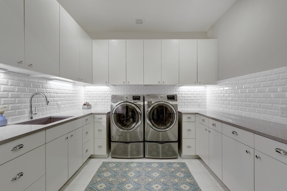 Inspiration for a large transitional u-shaped dedicated laundry room in Austin with an undermount sink, flat-panel cabinets, white cabinets, quartz benchtops, grey walls, porcelain floors, a side-by-side washer and dryer, white floor and grey benchtop.