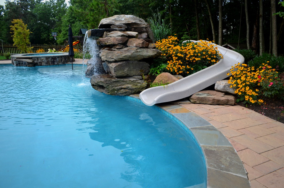 Example of a huge transitional backyard concrete paver and custom-shaped natural water slide design in DC Metro