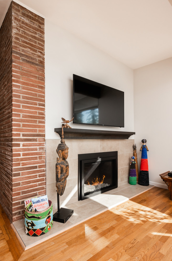 Idée de décoration pour une salle de séjour vintage de taille moyenne et ouverte avec un mur blanc, un sol en bois brun, une cheminée standard, un manteau de cheminée en carrelage, un téléviseur fixé au mur et un sol marron.
