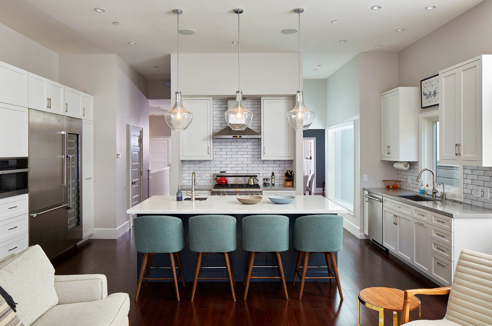 Photo of a transitional open plan kitchen in San Francisco with an undermount sink, shaker cabinets, white cabinets, white splashback, subway tile splashback, stainless steel appliances, medium hardwood floors and with island.