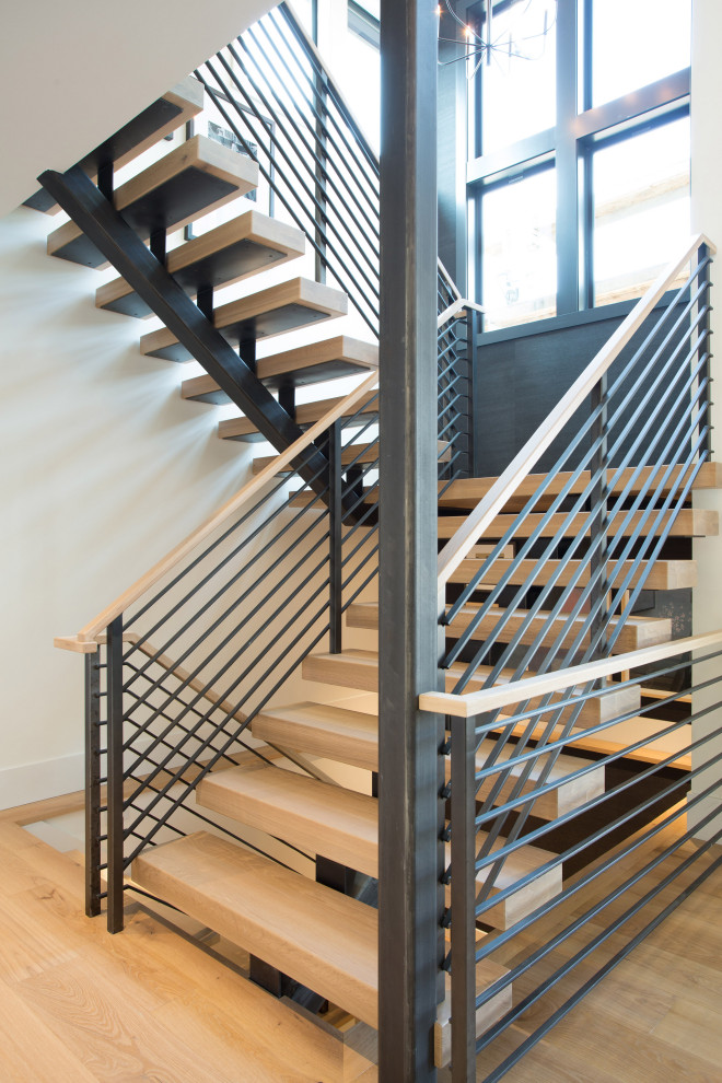 Exempel på en stor modern flytande trappa i trä, med öppna sättsteg och räcke i metall