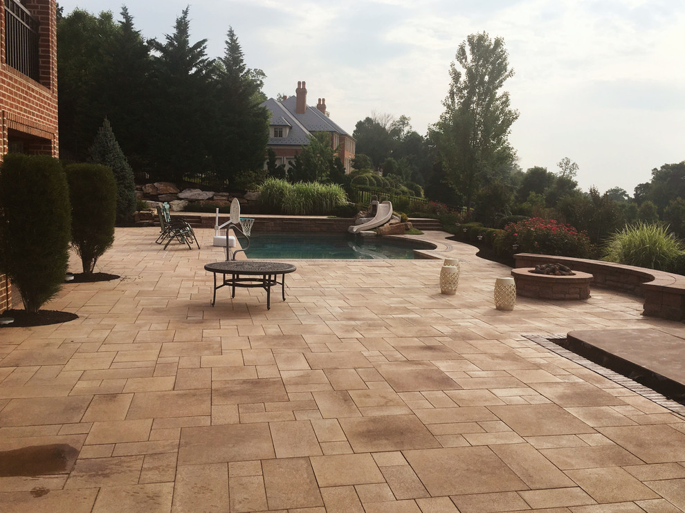 Photo of a mid-sized modern backyard custom-shaped pool in Philadelphia with a water slide and natural stone pavers.