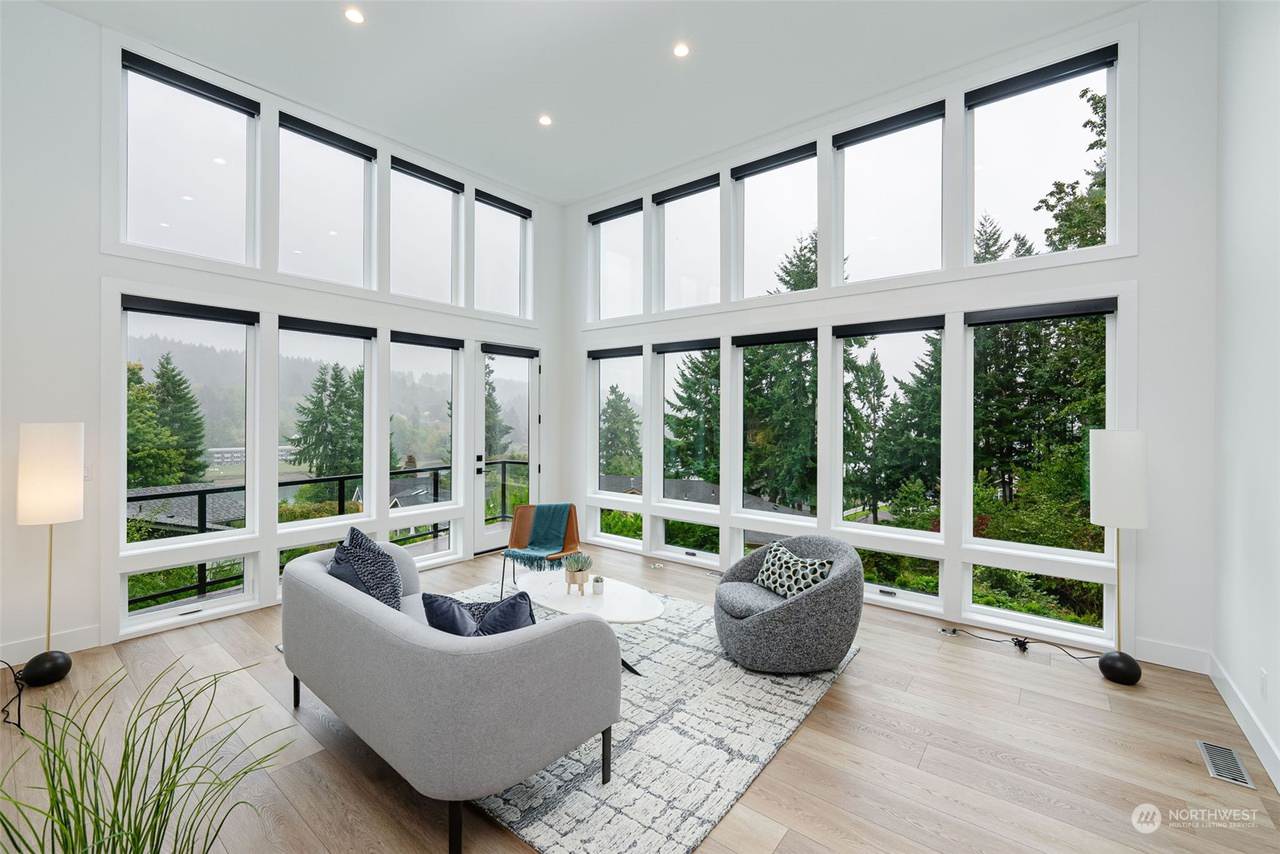 The living area during the day is filled with natural light from the large windows. The modern furnishings and high ceilings create a spacious and airy atmosphere, perfect for relaxation and entertain