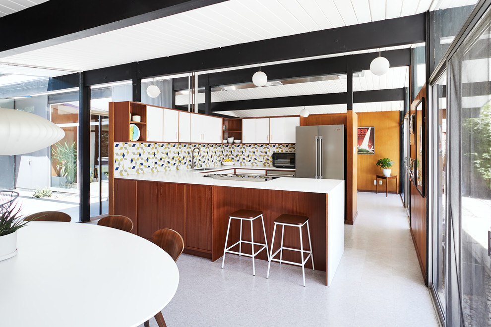 Photo of a midcentury u-shaped kitchen in San Francisco with an undermount sink, flat-panel cabinets, white cabinets, multi-coloured splashback, mosaic tile splashback, a peninsula, grey floor and white benchtop.