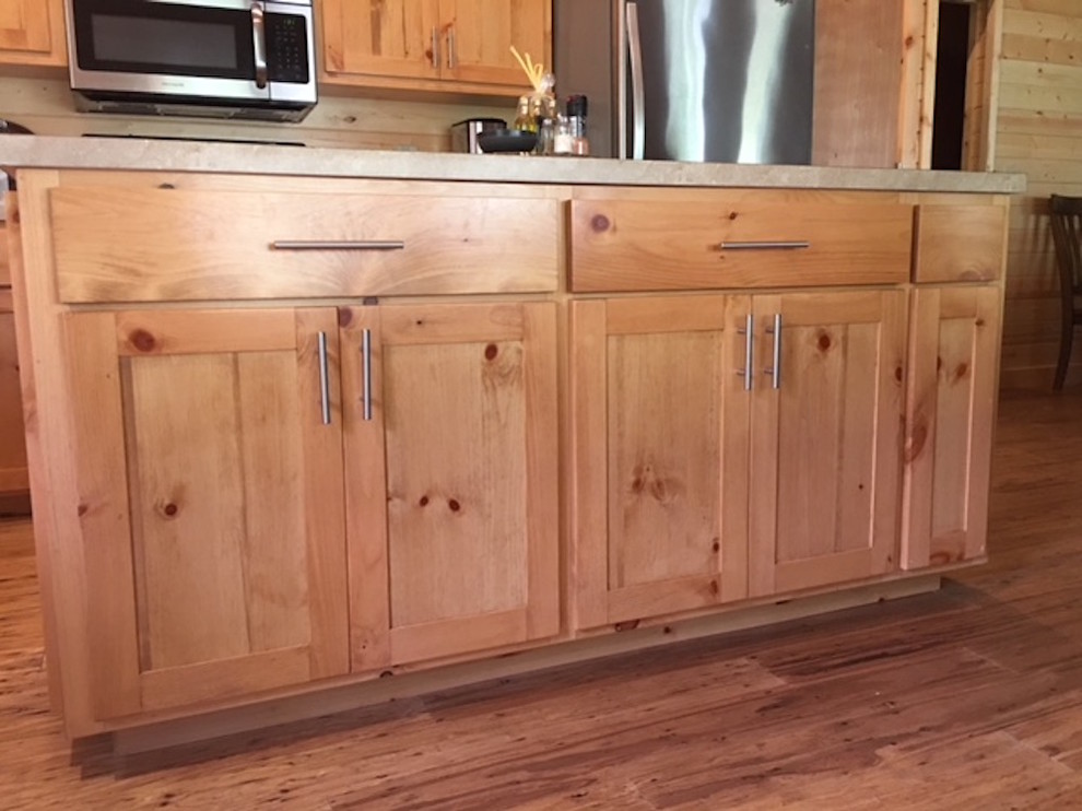 Large mountain style l-shaped medium tone wood floor and brown floor kitchen photo with a double-bowl sink, shaker cabinets, light wood cabinets, solid surface countertops, brown backsplash, wood backsplash and stainless steel appliances