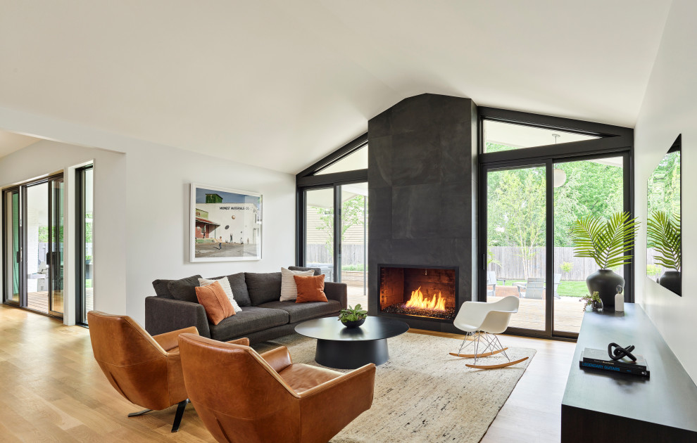 Living room - mid-sized modern open concept light wood floor and vaulted ceiling living room idea in Kansas City with white walls, a wood stove, a brick fireplace and a wall-mounted tv