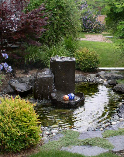 This is an example of a country front yard garden in Seattle with a water feature.