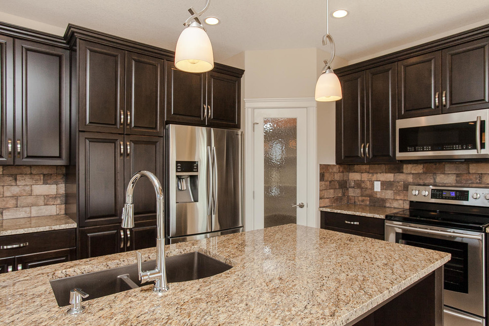 Enclosed kitchen - mid-sized transitional l-shaped enclosed kitchen idea in Edmonton with an undermount sink, raised-panel cabinets, dark wood cabinets, granite countertops, brown backsplash, subway tile backsplash, stainless steel appliances, an island and brown countertops
