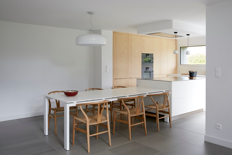 Photo of a mid-sized scandinavian l-shaped eat-in kitchen in Lille with beaded inset cabinets, stainless steel benchtops, white splashback, ceramic floors, with island, white cabinets and grey floor.