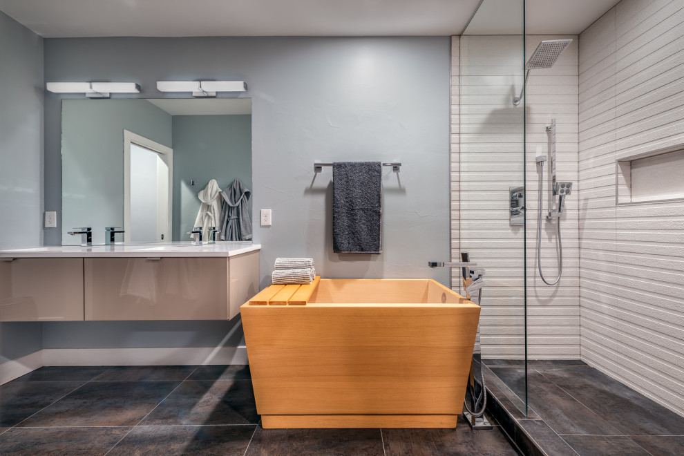 Design ideas for a large contemporary master wet room bathroom in Denver with flat-panel cabinets, beige cabinets, a japanese tub, a one-piece toilet, blue walls, light hardwood floors, an undermount sink, solid surface benchtops, beige floor, an open shower and white benchtops.