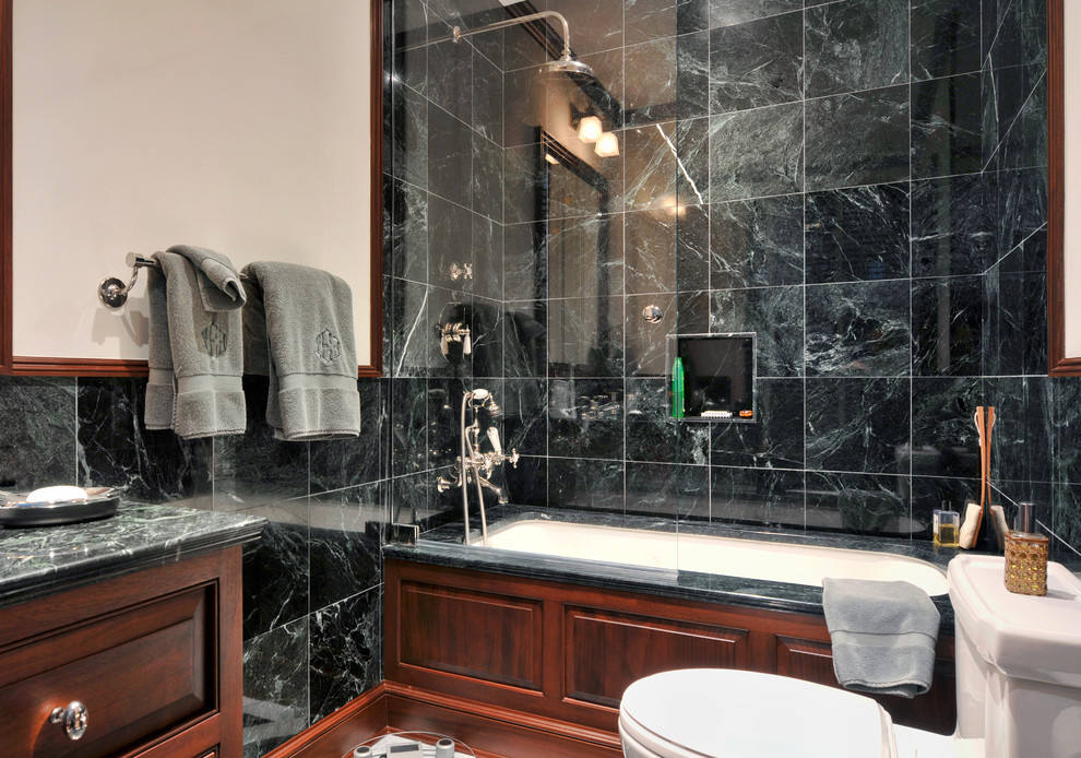 Photo of a mid-sized traditional master bathroom in New York with a drop-in sink, furniture-like cabinets, medium wood cabinets, marble benchtops, an alcove tub, a shower/bathtub combo, a two-piece toilet, green tile, stone tile, white walls and marble floors.