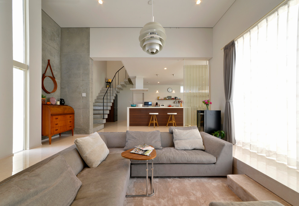 This is an example of a contemporary open concept living room in Other with white walls and beige floor.