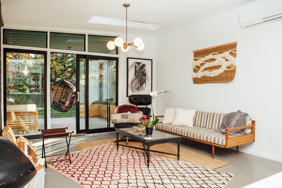 Design ideas for a midcentury family room in Denver with white walls and concrete floors.