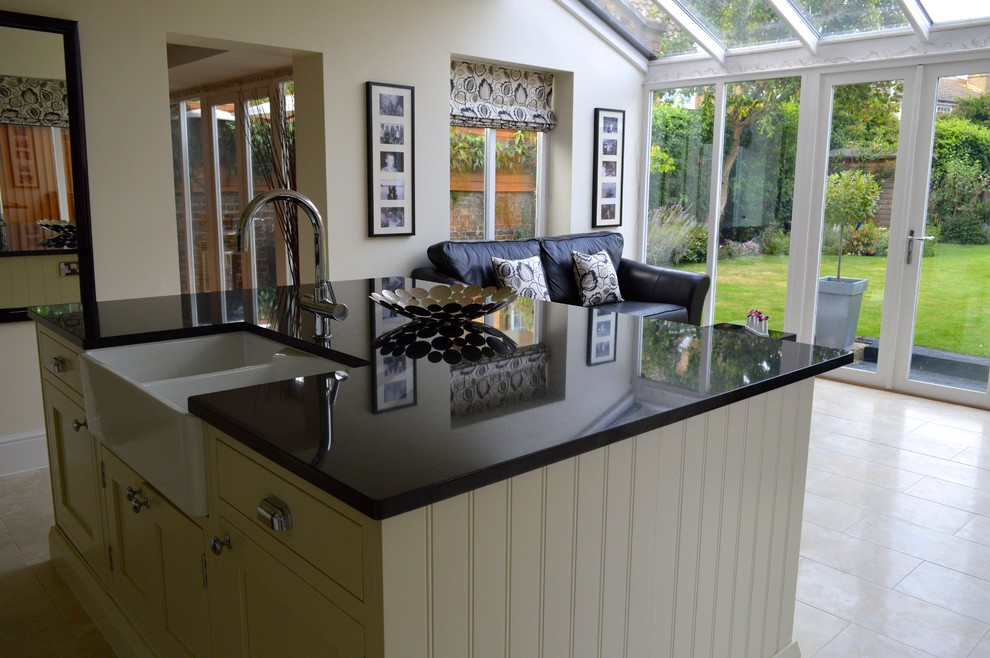 This is an example of a mid-sized traditional separate kitchen in Essex with an undermount sink, shaker cabinets, beige cabinets, granite benchtops, black splashback, stone slab splashback, stainless steel appliances, porcelain floors and with island.