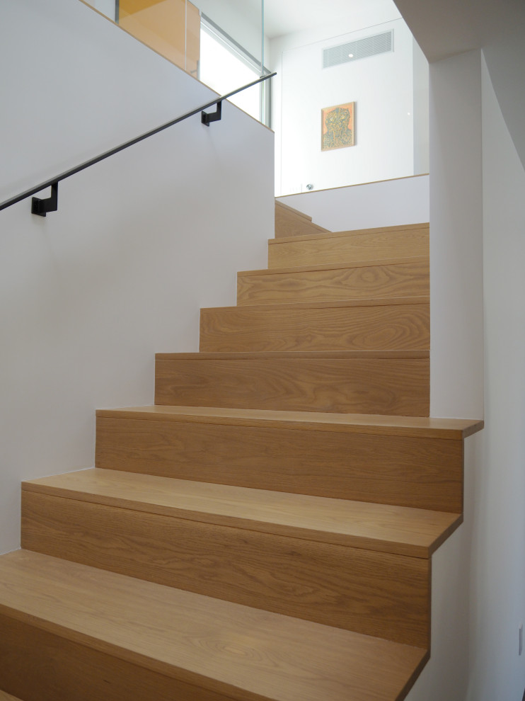 Foto de escalera en L minimalista grande con escalones de madera, contrahuellas de madera y barandilla de metal