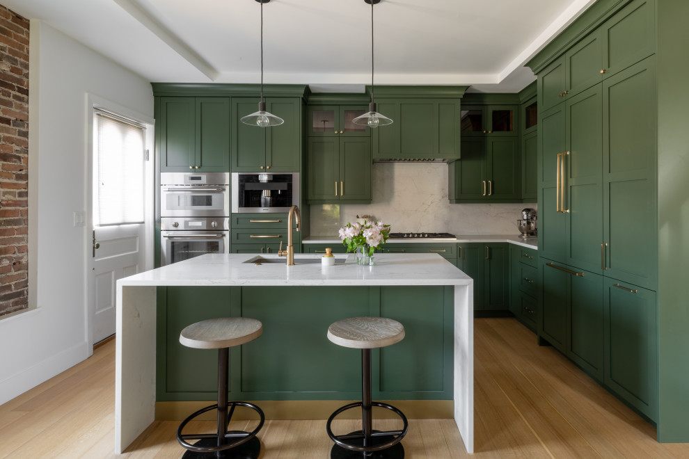 Large transitional l-shaped light wood floor, brown floor and tray ceiling eat-in kitchen photo in Detroit with an undermount sink, shaker cabinets, green cabinets, quartz countertops, white backsplash, quartz backsplash, stainless steel appliances, an island and white countertops