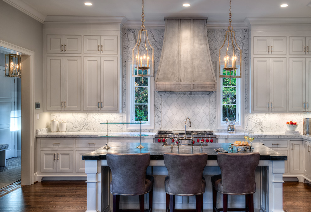Open concept kitchen - mid-sized transitional l-shaped dark wood floor open concept kitchen idea with a farmhouse sink, beaded inset cabinets, white cabinets, marble countertops, white backsplash, stone slab backsplash, stainless steel appliances and an island