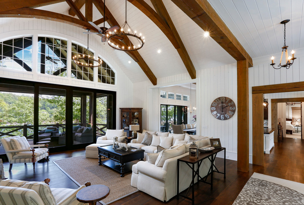 Photo of a large beach style open concept living room in Atlanta with white walls, medium hardwood floors, a standard fireplace, a stone fireplace surround, a wall-mounted tv and brown floor.