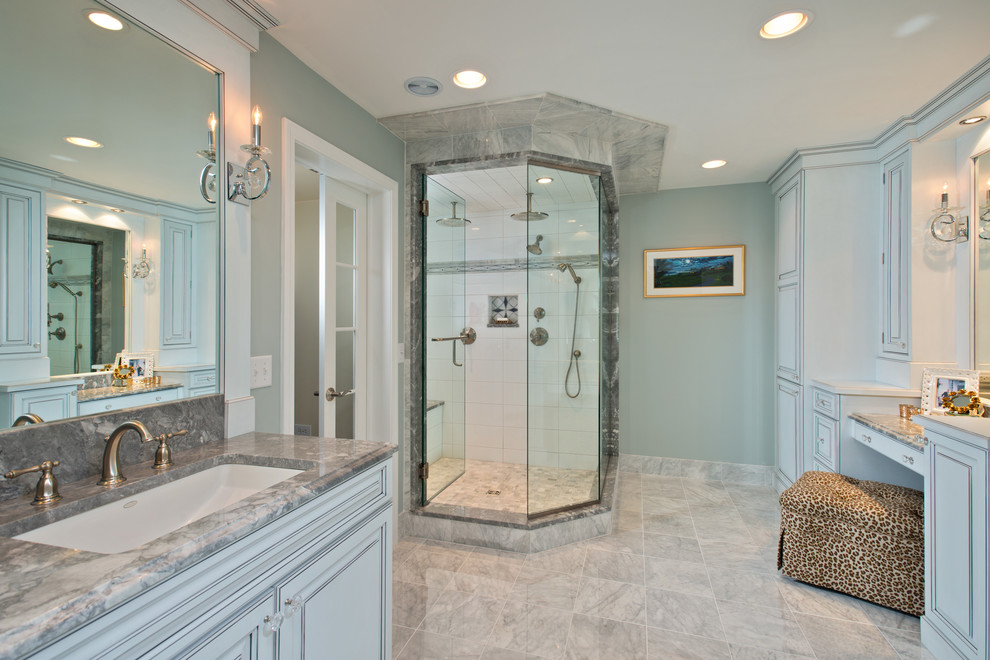 Design ideas for a large traditional master bathroom in New York with an undermount sink, raised-panel cabinets, grey cabinets, a corner shower, gray tile, granite benchtops, a freestanding tub, a one-piece toilet, stone slab, blue walls and marble floors.