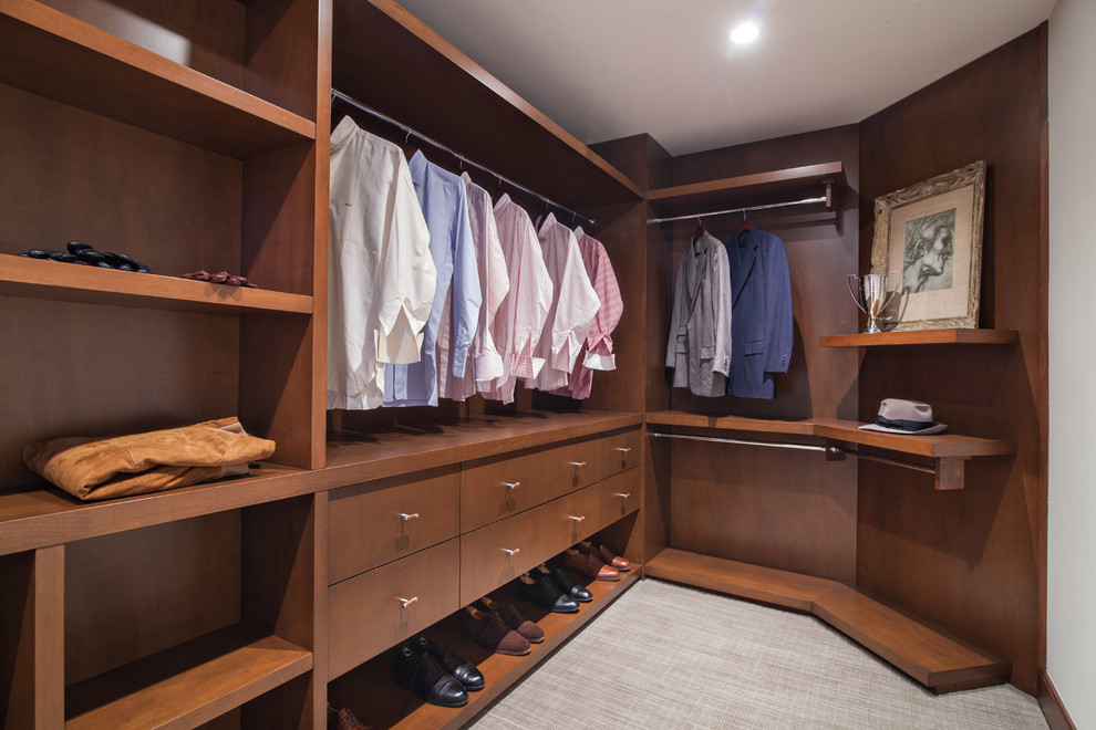 Inspiration for a mid-sized modern men's walk-in wardrobe in Miami with flat-panel cabinets, dark wood cabinets, carpet and beige floor.