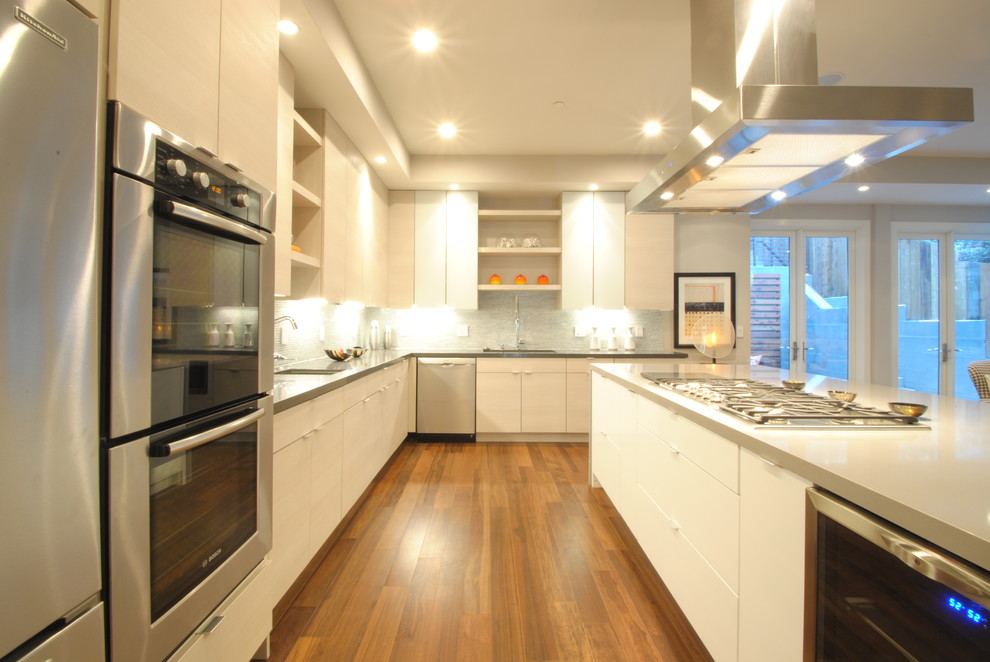 Inspiration for a large contemporary l-shaped eat-in kitchen in San Francisco with glass-front cabinets, white cabinets, quartz benchtops, blue splashback, stainless steel appliances, medium hardwood floors and with island.