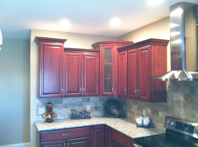 Example of a large galley light wood floor enclosed kitchen design in Cedar Rapids with a drop-in sink, flat-panel cabinets, black cabinets, metallic backsplash and an island