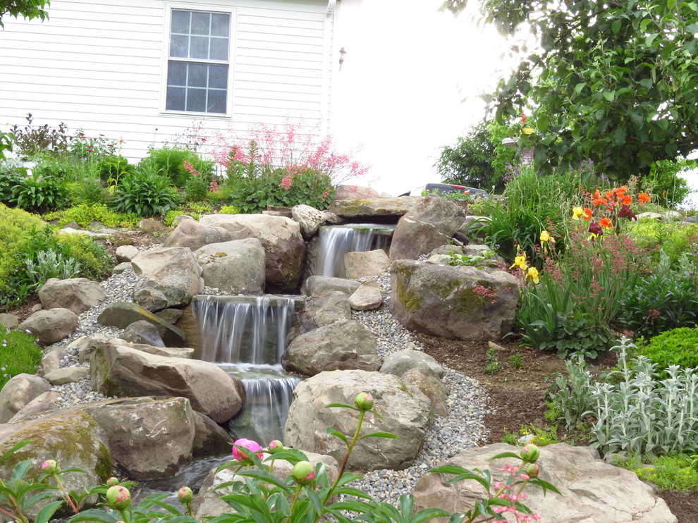 This is an example of a large eclectic sloped partial sun formal garden in New York with a water feature and gravel.