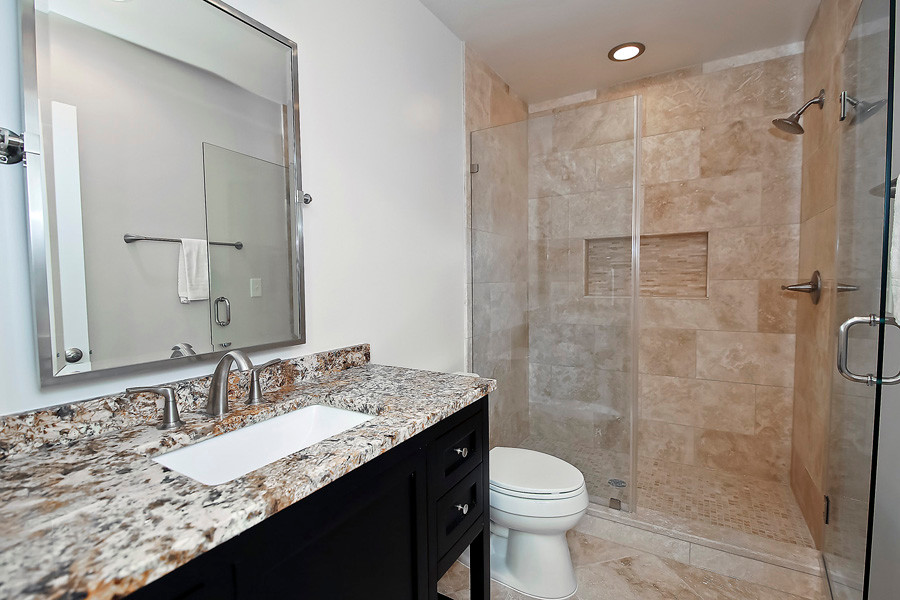 Photo of a small traditional 3/4 bathroom in DC Metro with shaker cabinets, dark wood cabinets, an alcove shower, a two-piece toilet, beige walls, porcelain floors, an undermount sink and granite benchtops.