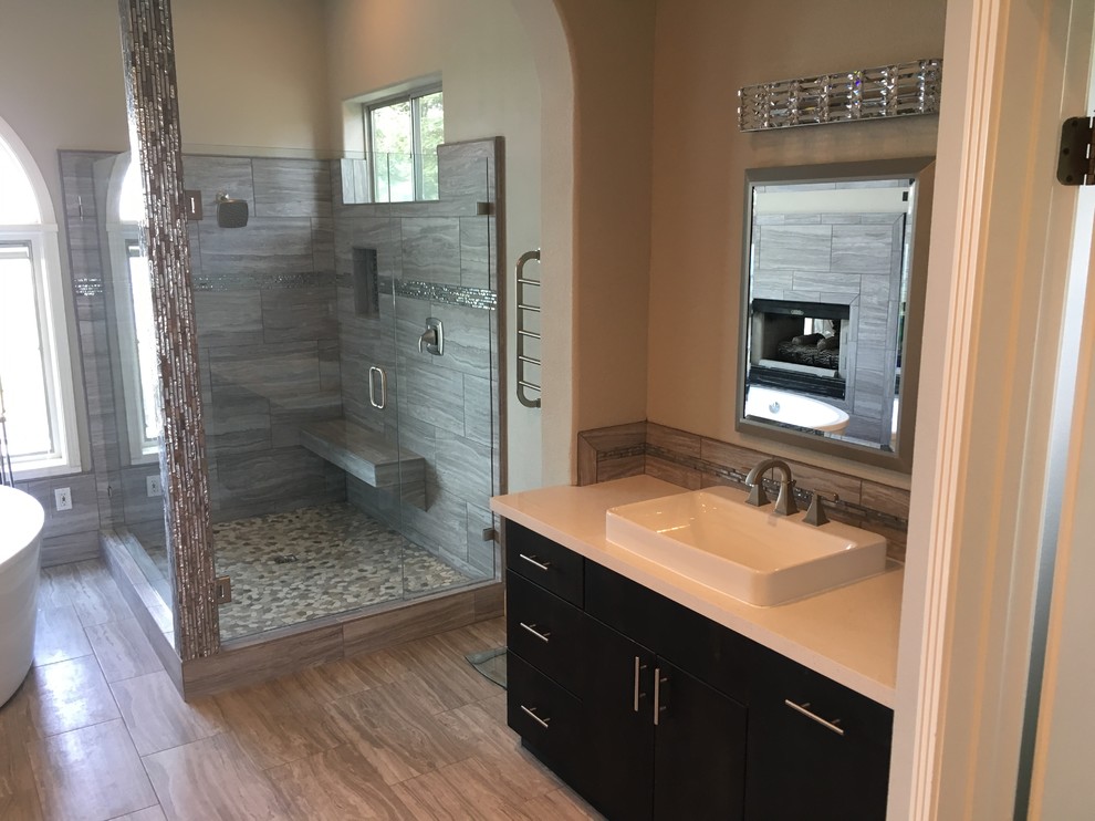 Minimalist master ceramic tile and gray floor freestanding bathtub photo with flat-panel cabinets, dark wood cabinets, a drop-in sink, quartzite countertops, a hinged shower door and white countertops