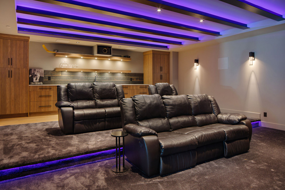 This is an example of a large contemporary enclosed home cinema in Vancouver with a projector screen and feature lighting.