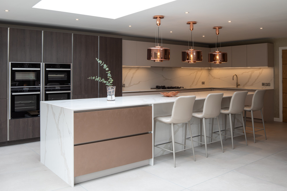 Photo of a large contemporary l-shaped open plan kitchen in West Midlands with a double-bowl sink, flat-panel cabinets, beige cabinets, marble benchtops, white splashback, marble splashback, panelled appliances, porcelain floors, with island, grey floor, white benchtop and coffered.