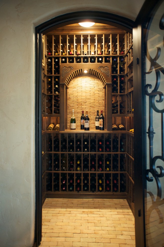 Small mediterranean wine cellar in Los Angeles with brick floors and storage racks.