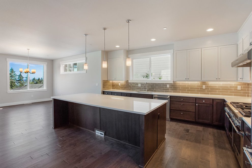 This is an example of a contemporary l-shaped open plan kitchen in Seattle with an undermount sink, shaker cabinets, white cabinets, quartzite benchtops, grey splashback, subway tile splashback, stainless steel appliances, dark hardwood floors, with island, brown floor and white benchtop.