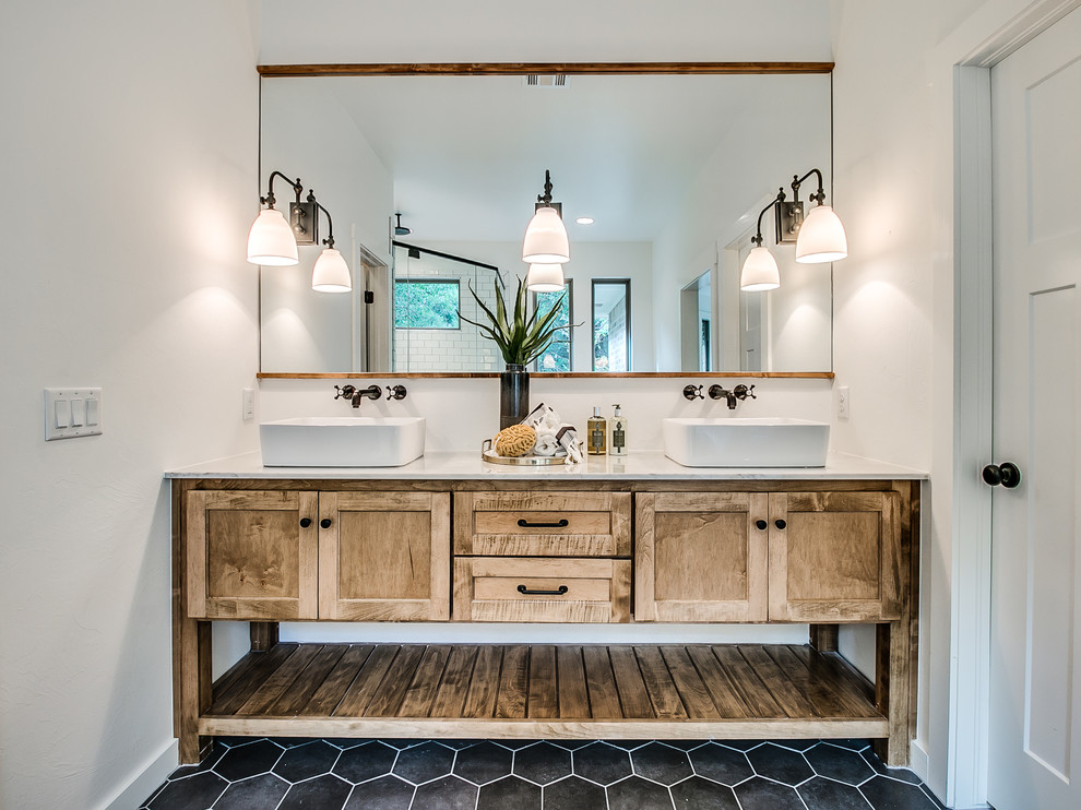 This is an example of a mid-sized country master bathroom in Oklahoma City with shaker cabinets, medium wood cabinets, a freestanding tub, a double shower, a one-piece toilet, white tile, subway tile, white walls, ceramic floors, a vessel sink, marble benchtops, black floor and a hinged shower door.