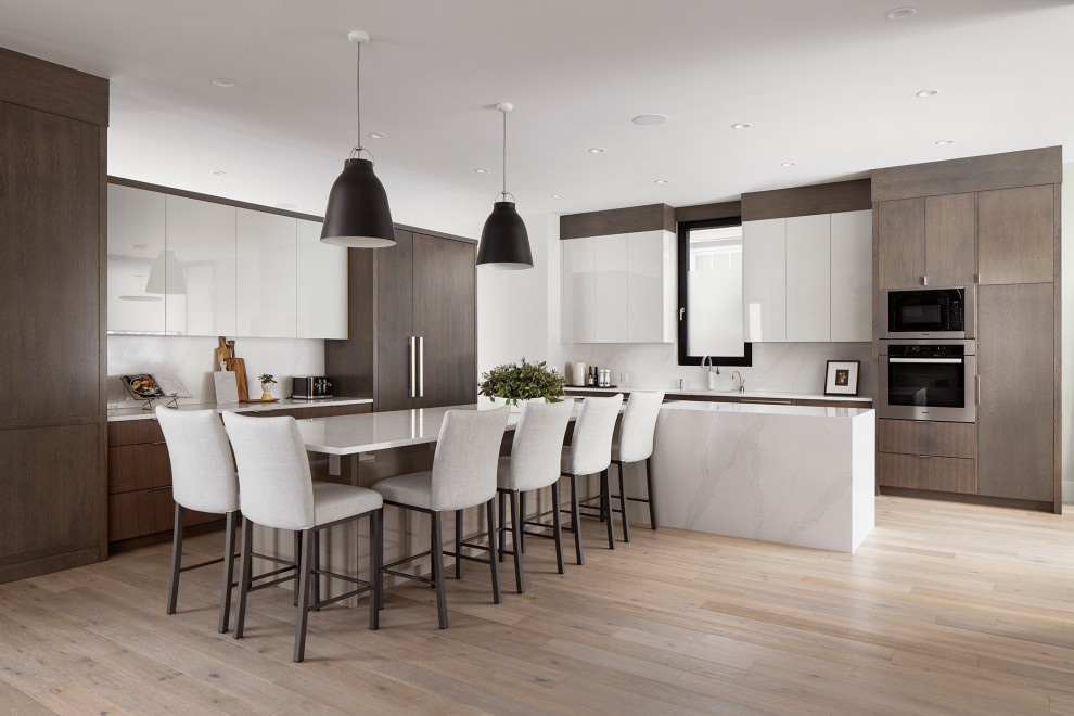 Kitchen - large modern l-shaped light wood floor kitchen idea in Calgary with a double-bowl sink, flat-panel cabinets, quartz countertops, quartz backsplash and an island