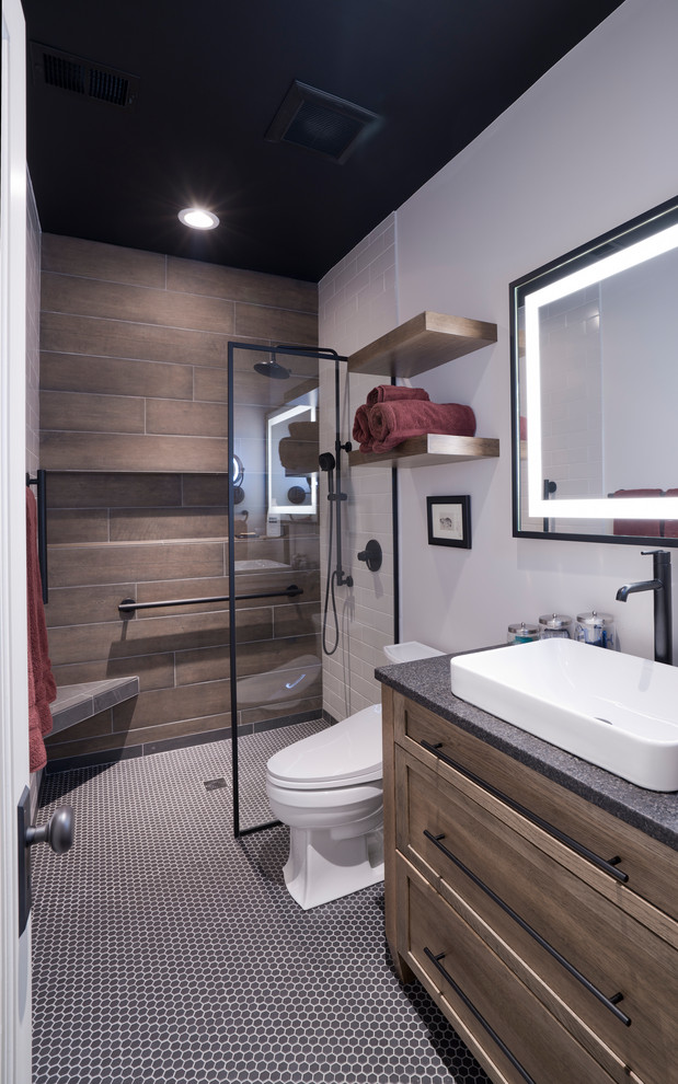 Idéer för mellanstora funkis svart en-suite badrum, med skåp i shakerstil, skåp i mellenmörkt trä, en kantlös dusch, en bidé, brun kakel, porslinskakel, grå väggar, mosaikgolv, ett fristående handfat, granitbänkskiva, svart golv och med dusch som är öppen