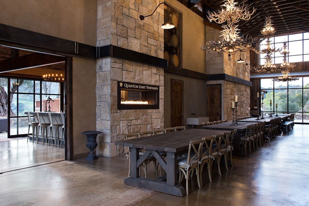 This is an example of a large industrial open plan dining in San Francisco with grey walls, concrete floors, a ribbon fireplace and a stone fireplace surround.