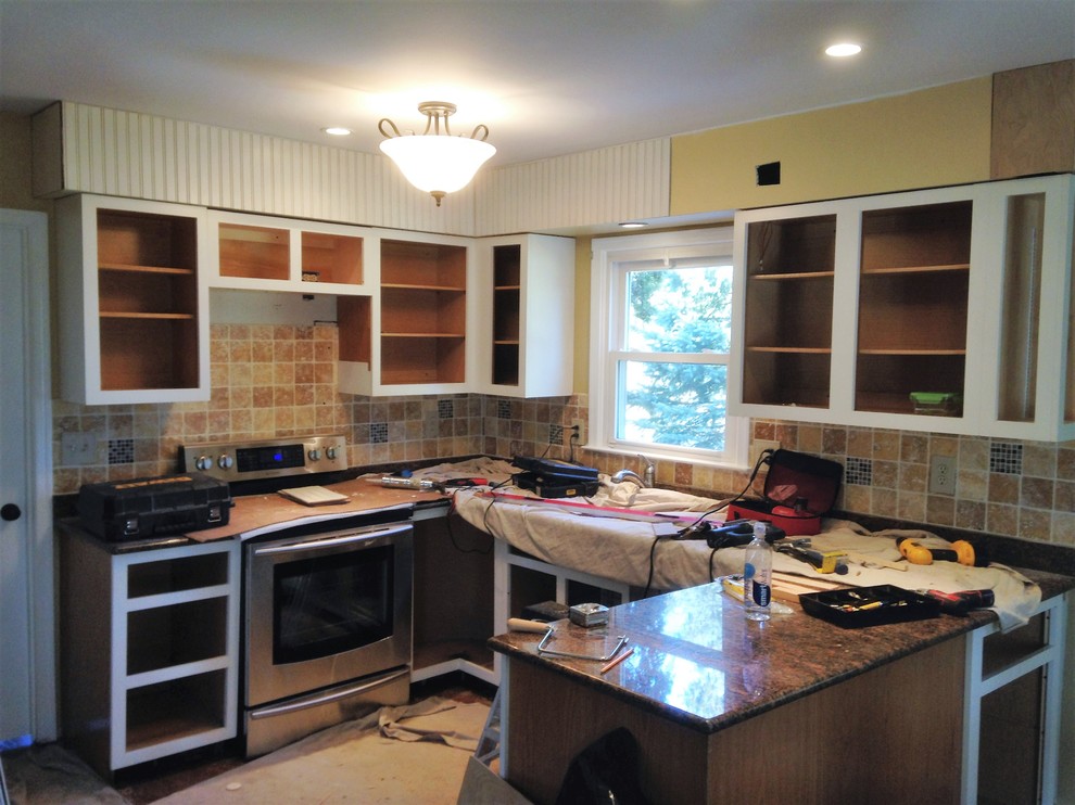 Mid-sized u-shaped dark wood floor eat-in kitchen photo in Philadelphia with an undermount sink, raised-panel cabinets, yellow cabinets, granite countertops, beige backsplash, ceramic backsplash, stainless steel appliances and a peninsula