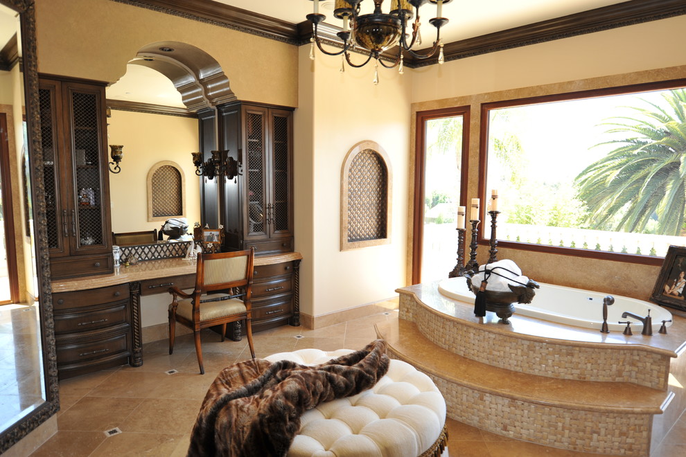 Inspiration for a mediterranean master bathroom in Orange County with a drop-in sink, furniture-like cabinets, dark wood cabinets, a drop-in tub, a double shower and a bidet.
