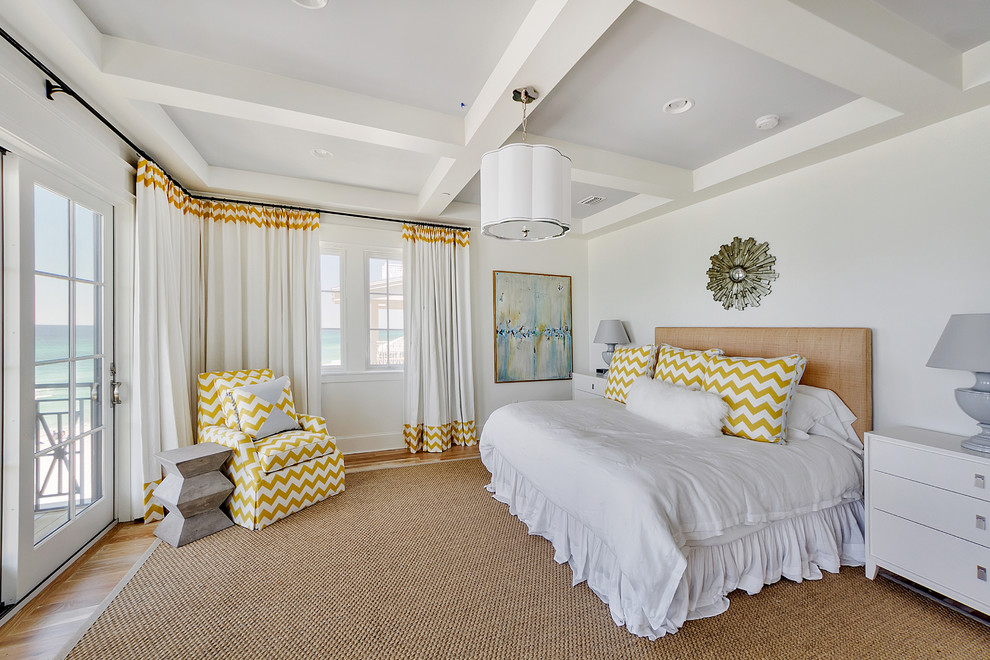 This is an example of a beach style bedroom in Miami with white walls and medium hardwood floors.