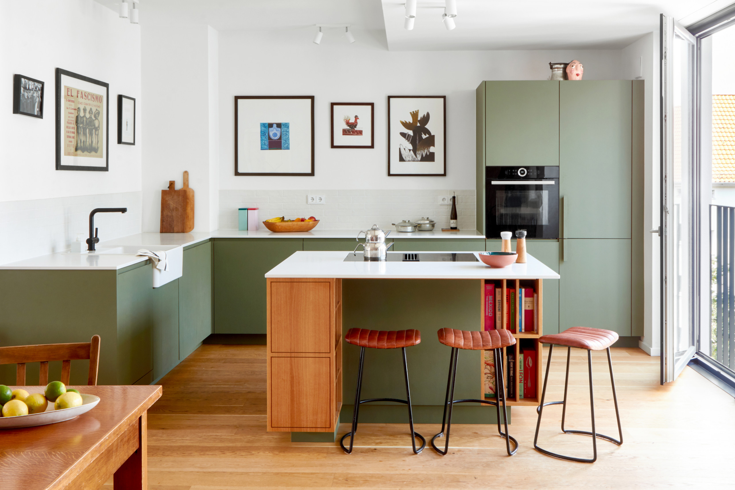 Eine grüne küche mit tisch und kühlschrank.